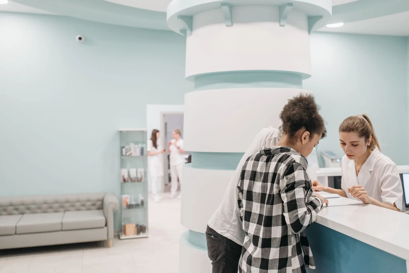 A patient and a receptionist across a clinic front desk